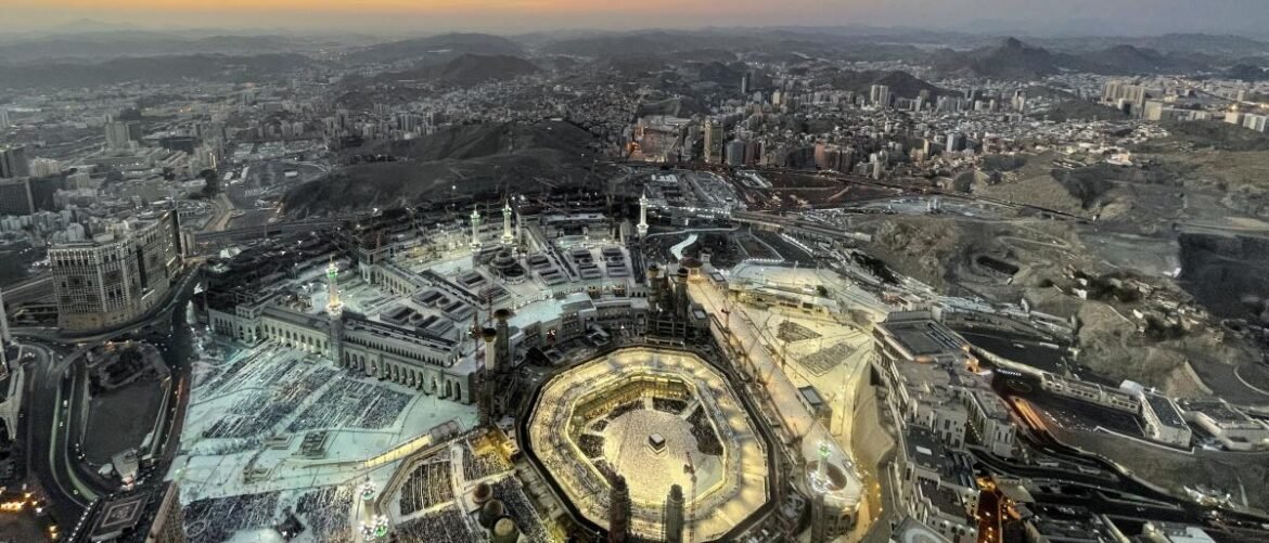 Aerial view of Masjid al-Haram in Mecca with the Kaaba at the center, surrounded by pilgrims and the mosque courtyards.