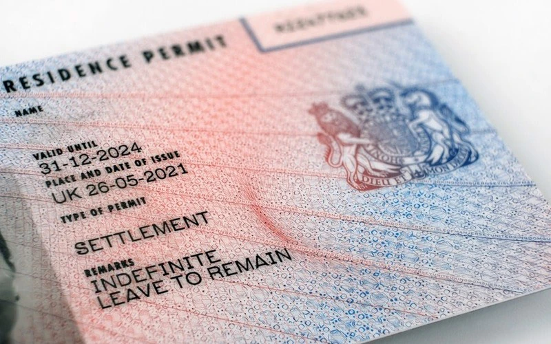 Uk Residence Permit Card Showing settlement and indefinite Leave to Remain with a Blue red Patterned Background and Crest on the Right  Aleumumnews