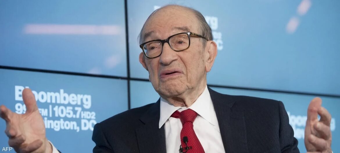 An elderly man in a dark suit and red tie speaks, gesturing with his hands in front of a blue backdrop with Bloomberg branding.