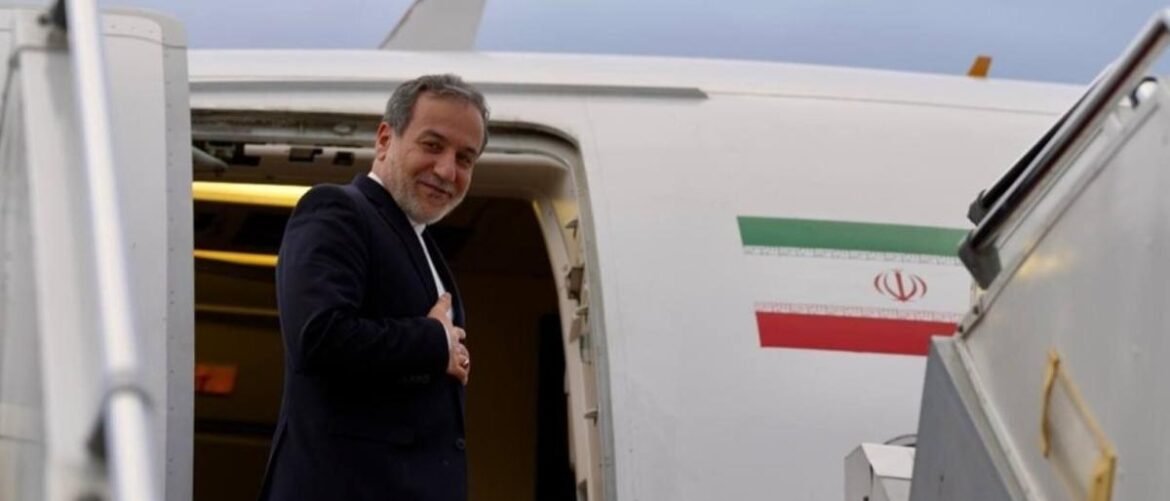 Man in a dark suit stepping off a white airplane with the Iran flag on the fuselage