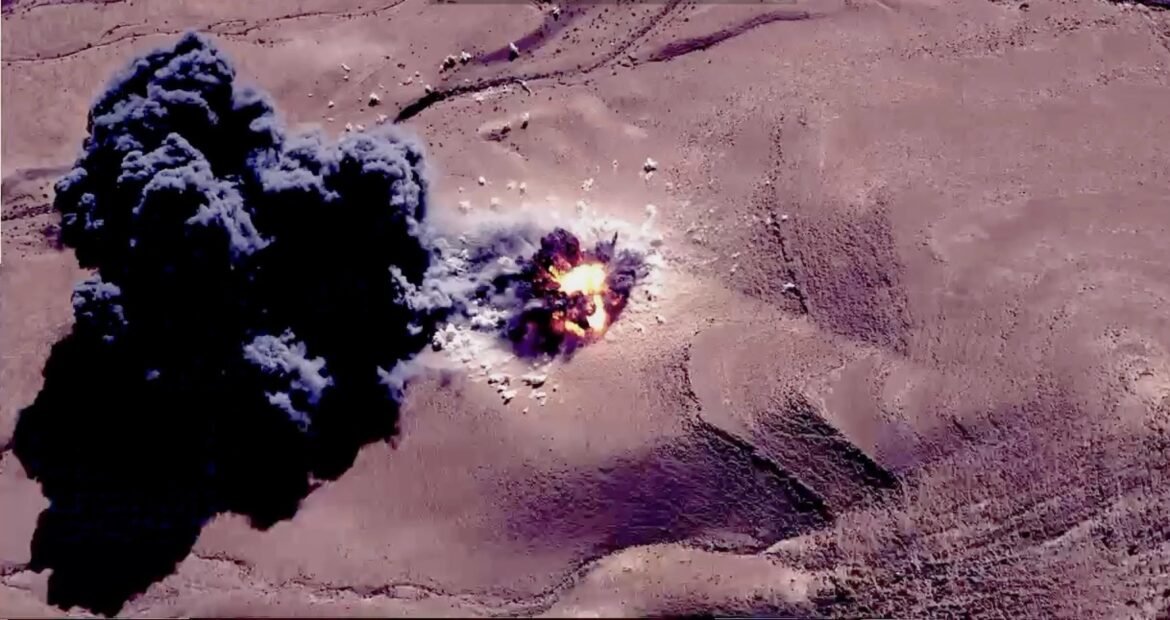 Explosive blast in a desert: dark smoke plume and bright orange flames rising from the ground.