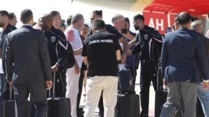 Group of Men in Matching Athletic Outfits Shake Hands and Greet Each Other with Rolling Suitcases Nearby at an Outdoor Event  Aleumumnews