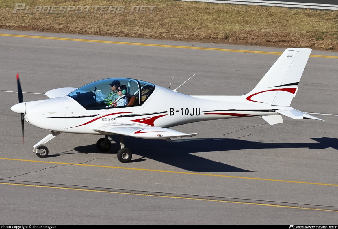 White single-engine propeller plane on a runway with two pilots inside the cockpit, preparing to taxi.