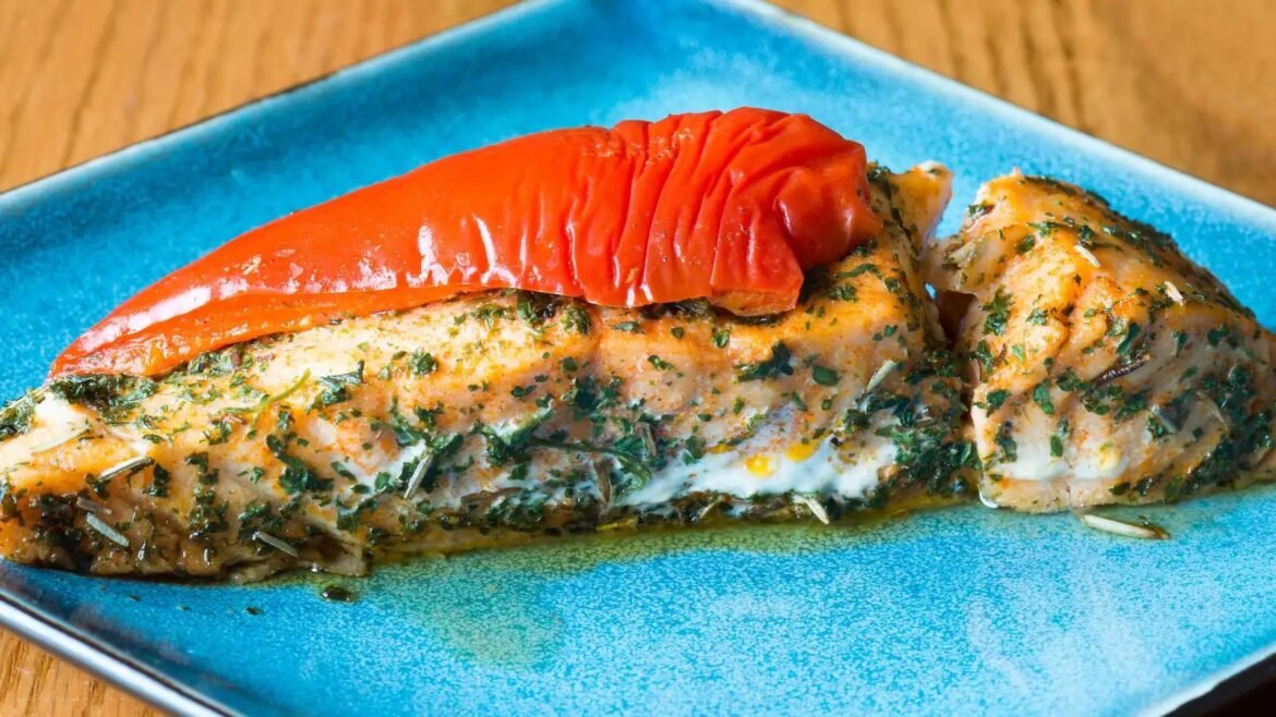 Herb-crusted salmon fillet topped with a roasted red pepper on a blue plate.