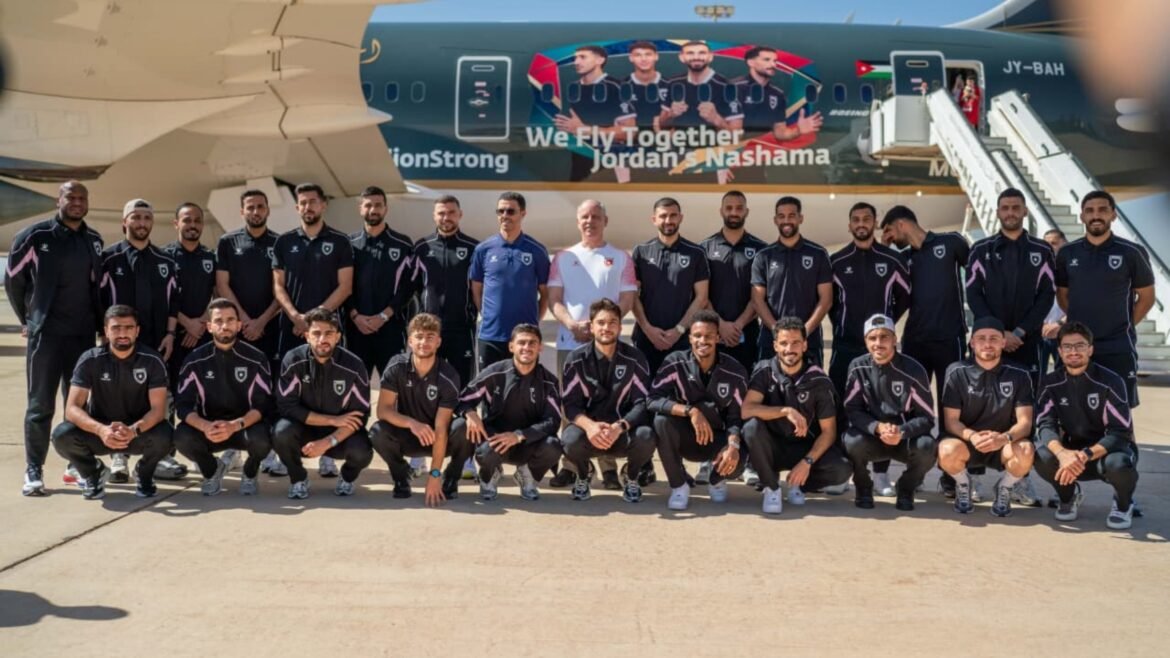 Group of male athletes in black uniforms posing for a team photo in front of a muraled airplane on the tarmac, with the banner 'We Fly Together' visible on the fuselage.