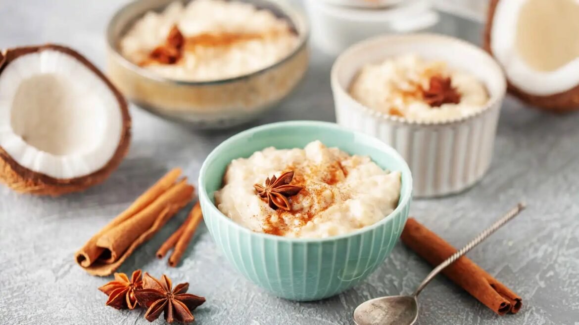 Creamy rice pudding in a turquoise bowl, garnished with cinnamon and star anise, with coconut and cinnamon sticks nearby.