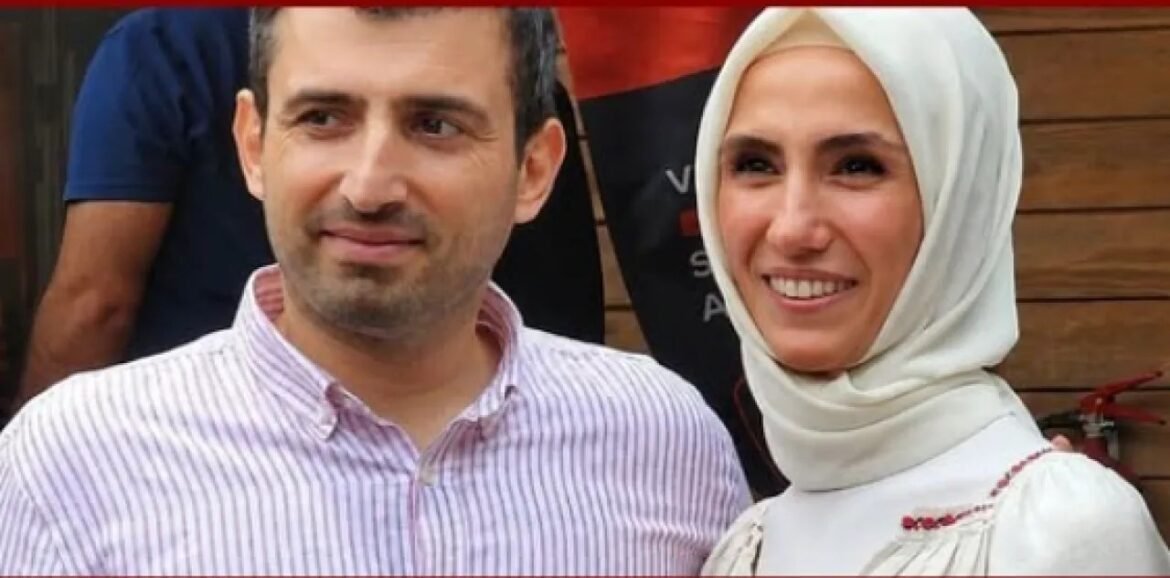 A man in a pink-striped shirt stands next to a smiling woman wearing a white hijab.