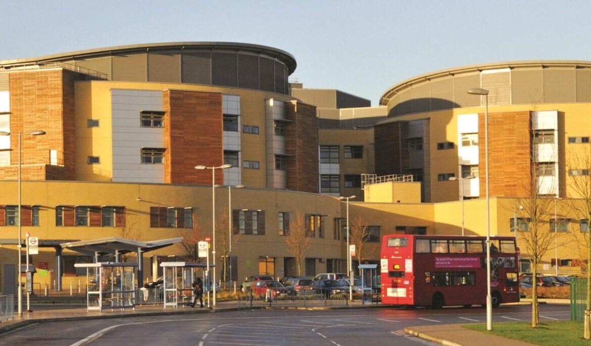 Red double-decker bus in front of a modern mixed-material campus-style building with yellow and brick façades.