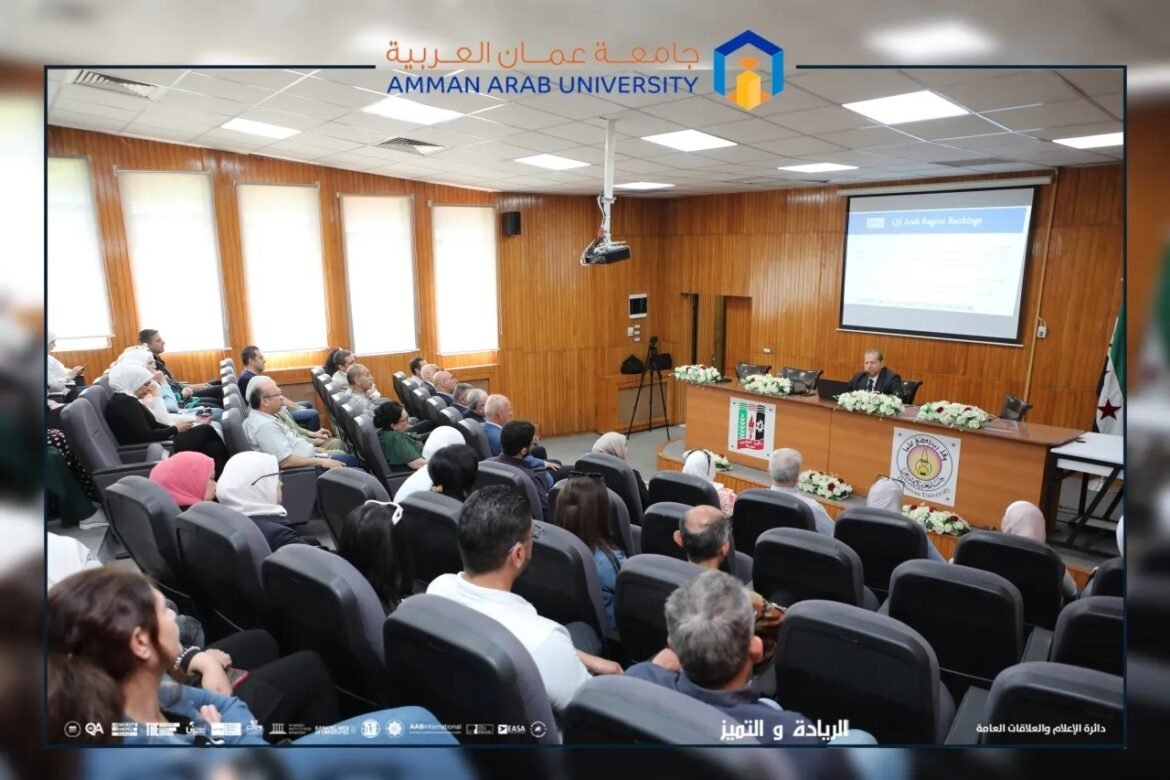 Lecture hall at Amman Arab University with attendees listening to a speaker at the front and a projected slide on screen.