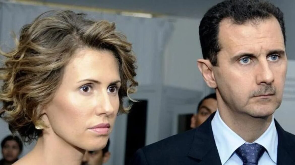 Two adults in a formal setting; woman with short wavy hair on the left and man in a dark suit on the right, both looking ahead.