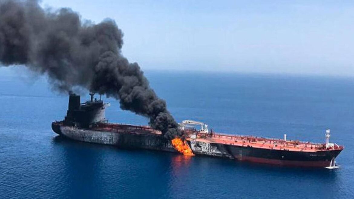 Oil tanker on fire with thick black smoke billowing from the midsection as flames emerge from the hull at sea.