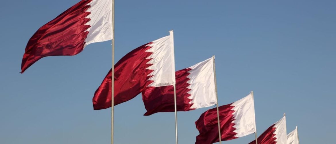 Row of white-and-maroon national flags waving in the wind against a clear blue sky