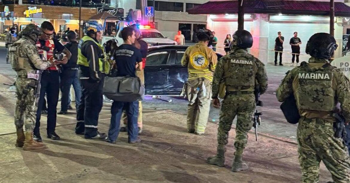 Group of responders, some wearing MARINA vests, stand near a car with flashing lights during a nighttime incident in a city street.
