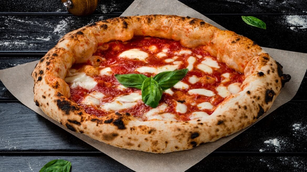 Neapolitan-style Margherita pizza topped with melted mozzarella and fresh basil on parchment paper.