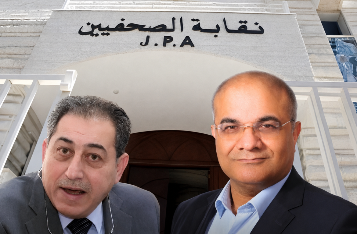 Two men in business suits posing for a selfie outside a stone building with Arabic signage reading J.P.A.