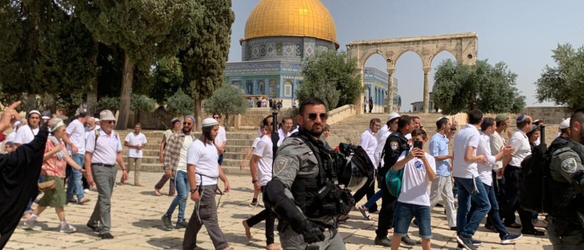 Crowd of tourists and security personnel walking near the Dome of the Rock in Jerusalem.