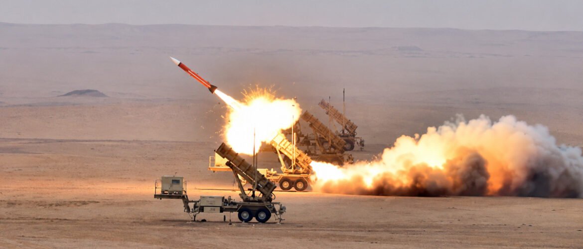 Military launch vehicles firing missiles on a desert test range, with bright flames and smoke trailing behind the rocket across a flat, barren landscape.