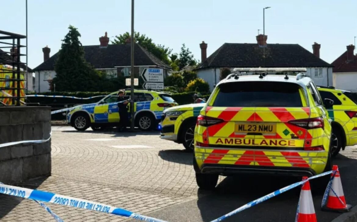Ambulance and police cars cordoned off with blue tape on a residential street.