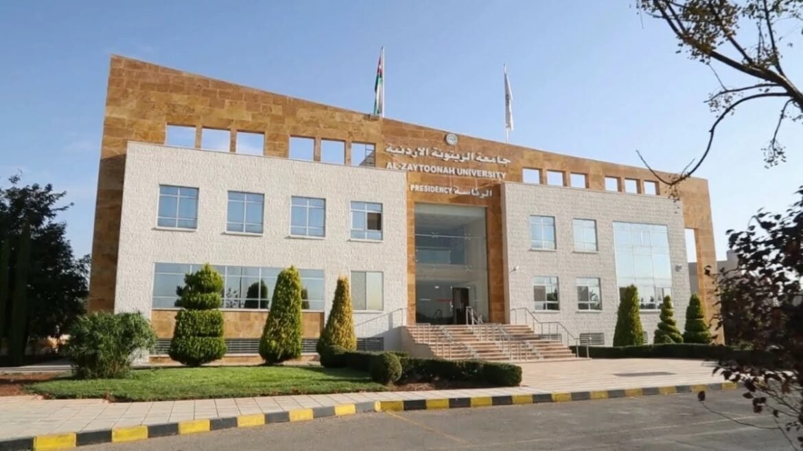 Front view of Al-Zaytoonah University building with a central glass entrance, steps, and trimmed evergreen shrubs; flagpoles atop the facade.