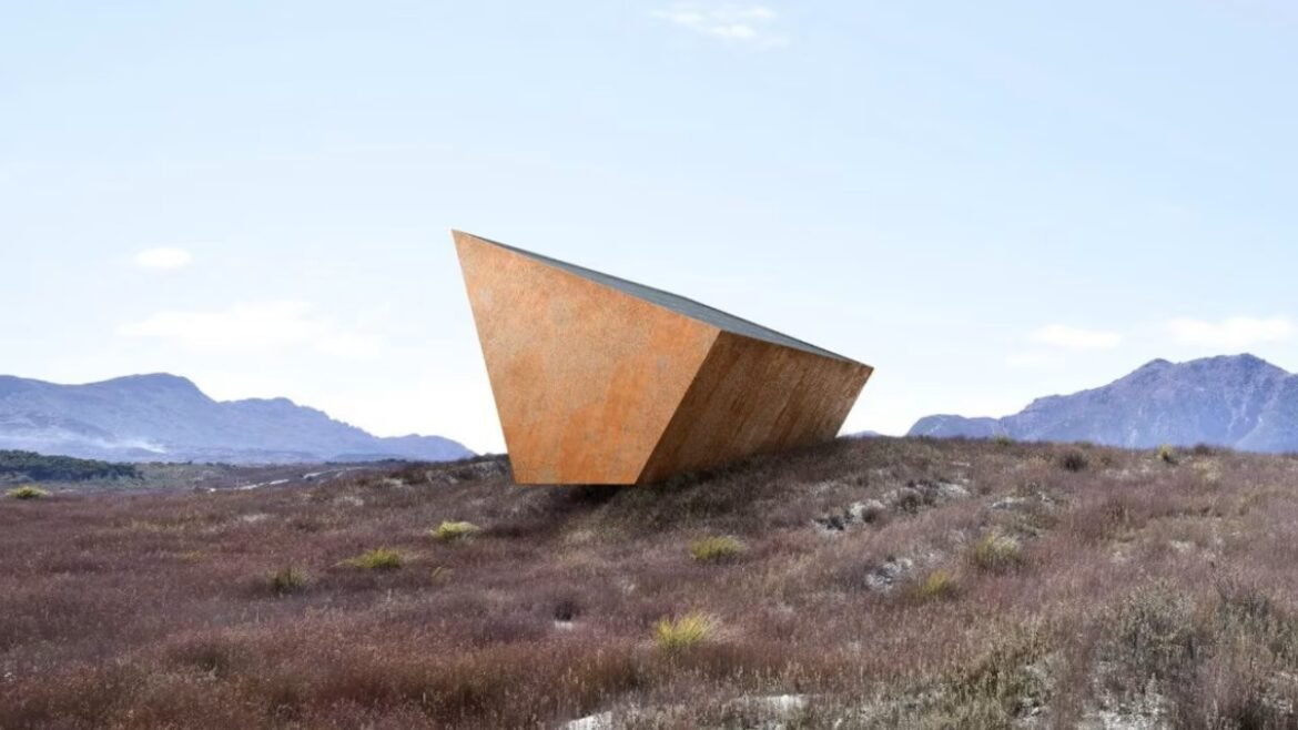 Rusty angular metal sculpture on a dry grassy plain with distant mountains under a clear blue sky.
