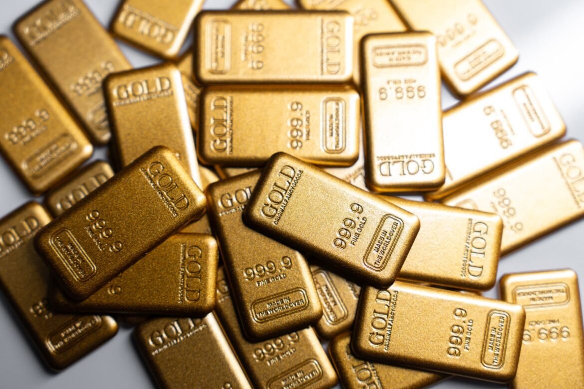 Pile of gold bars stacked together, stamped with GOLD and fineness marks like 999.9 (gold bullion)