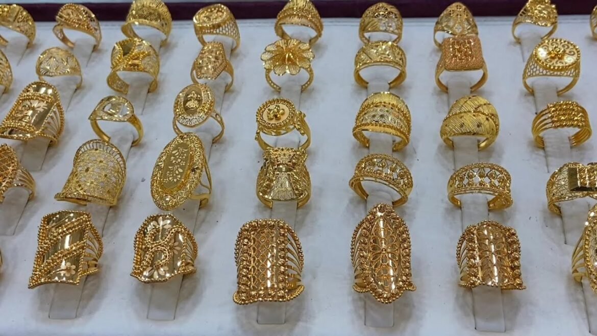 Row of ornate gold rings on a white display stand.