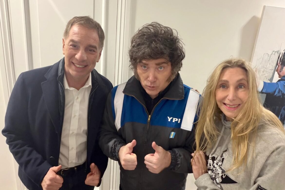 Three people pose for a selfie indoors, smiling at the camera in a hallway.