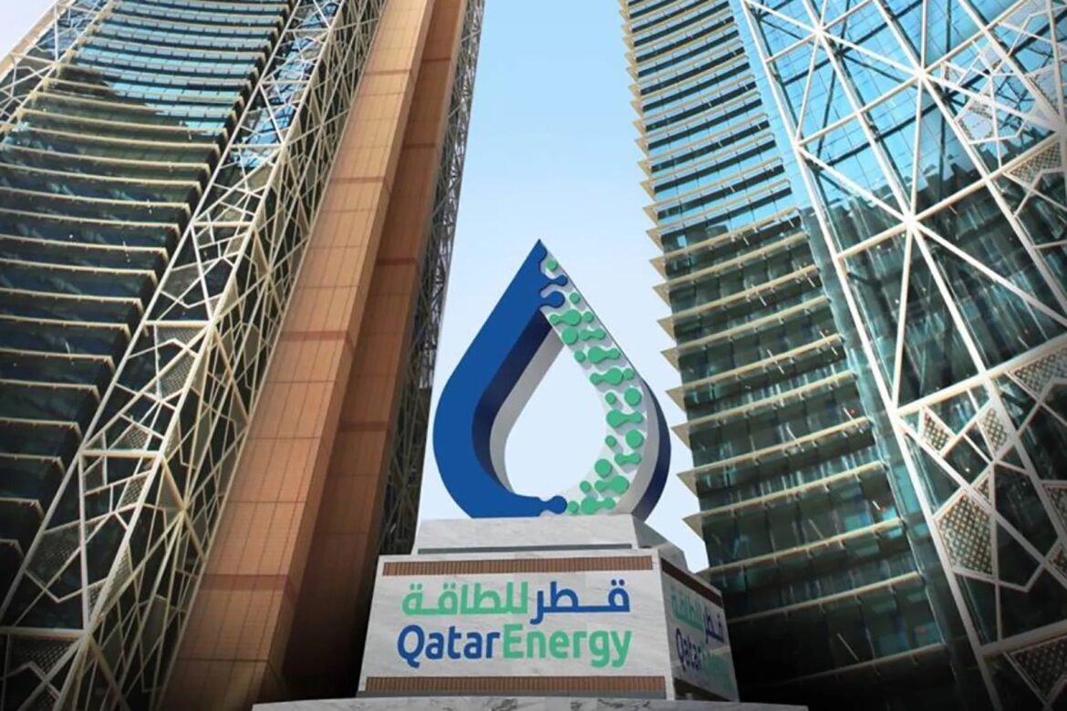 QatarEnergy sign with its logo between two tall glass office towers against a blue sky.
