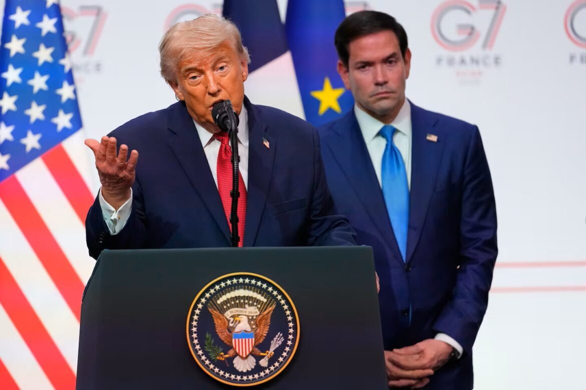 Speaker at a podium bearing the presidential seal, mic in front, with a suited aide standing behind in a formal briefing setting.