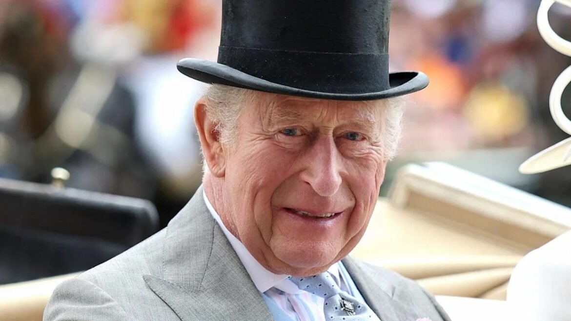 Older man in a light gray suit and top hat, smiling at a formal outdoor event.