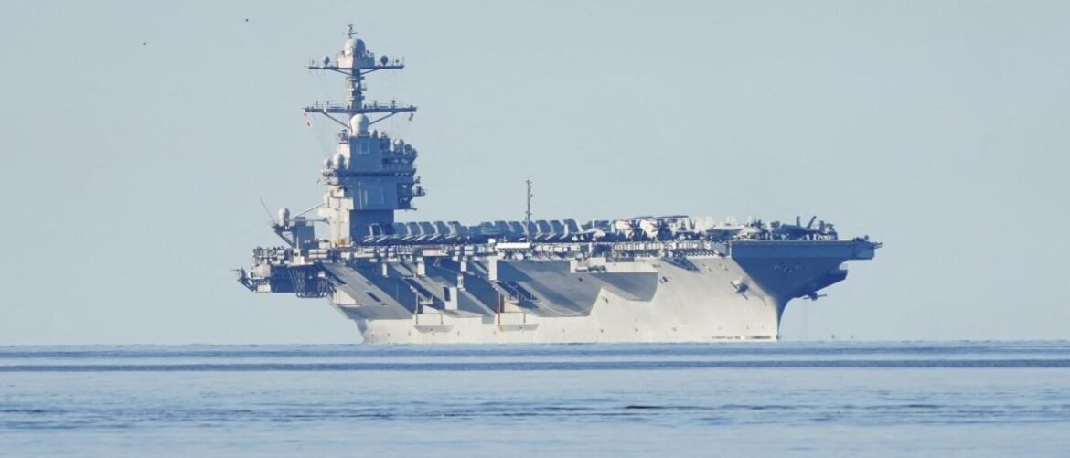 Aircraft carrier sailing on calm sea, side view showing the flight deck and island superstructure.