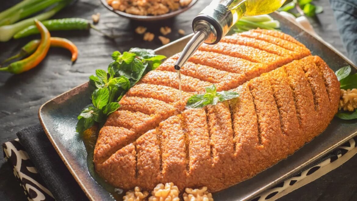 Sliced loaf of nut or lentil roast on a platter with fresh mint, olive oil being drizzled over top.