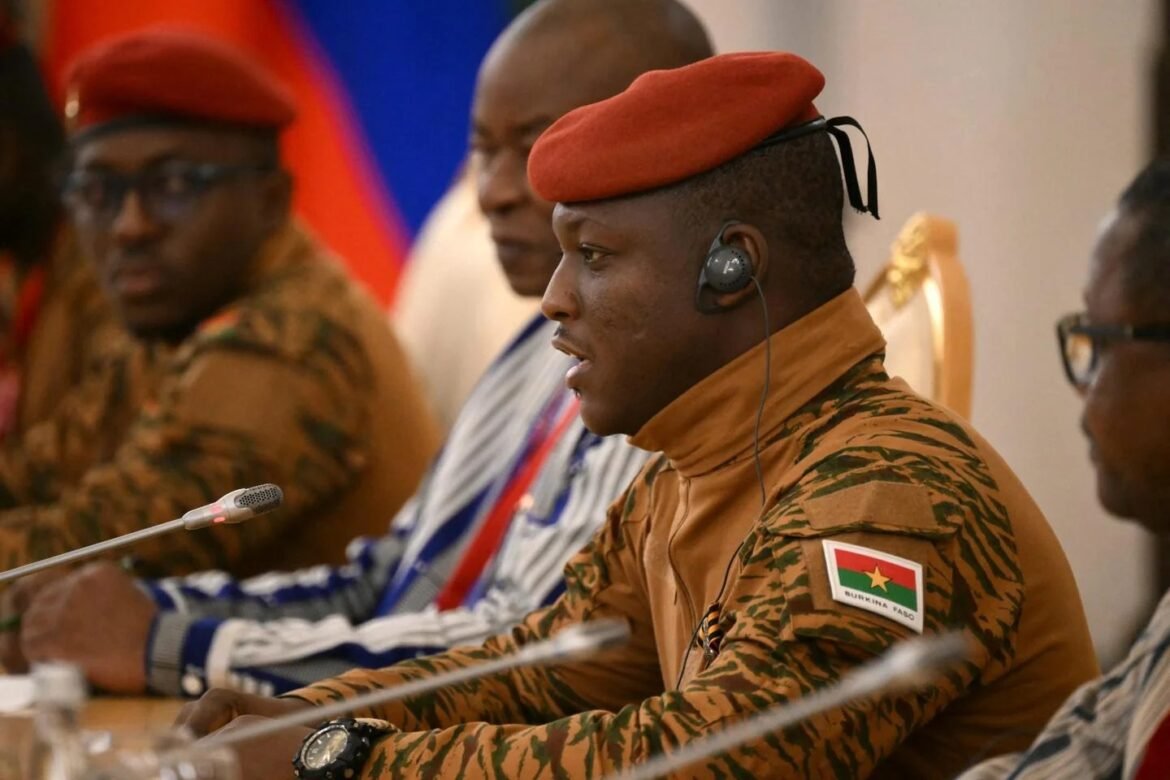Burkina Faso soldier in camouflage uniform and red beret speaking into a microphone at a panel.