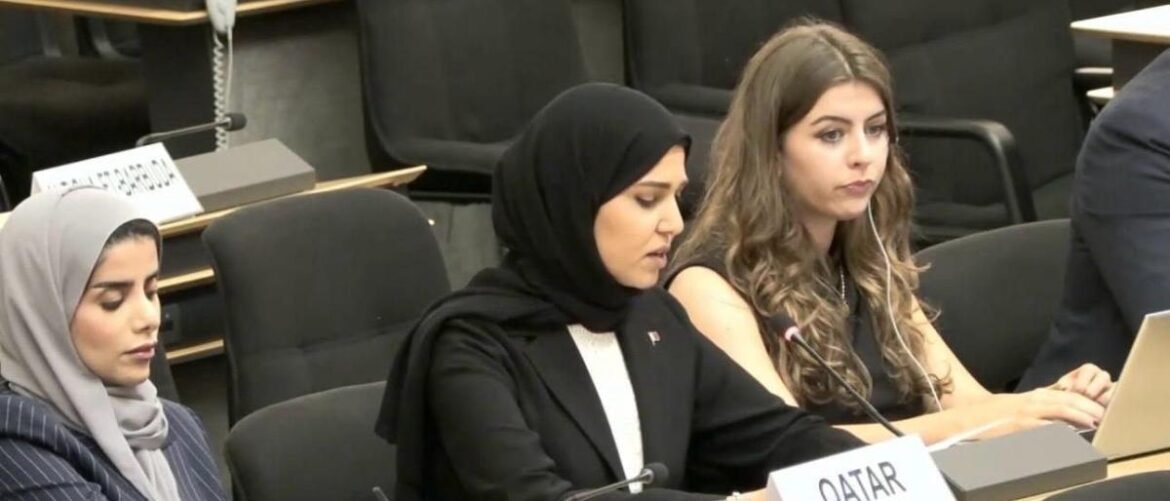 Panel of three women at a conference; middle woman in a black hijab speaks into a microphone, right woman with long wavy hair, Qatar sign visible on the table.