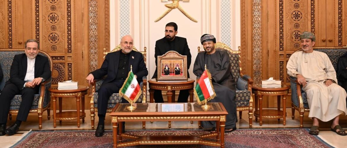 Formal diplomatic meeting in a gold-toned room; five men sit on ornate chairs with Iran and Oman flags on side tables between them.