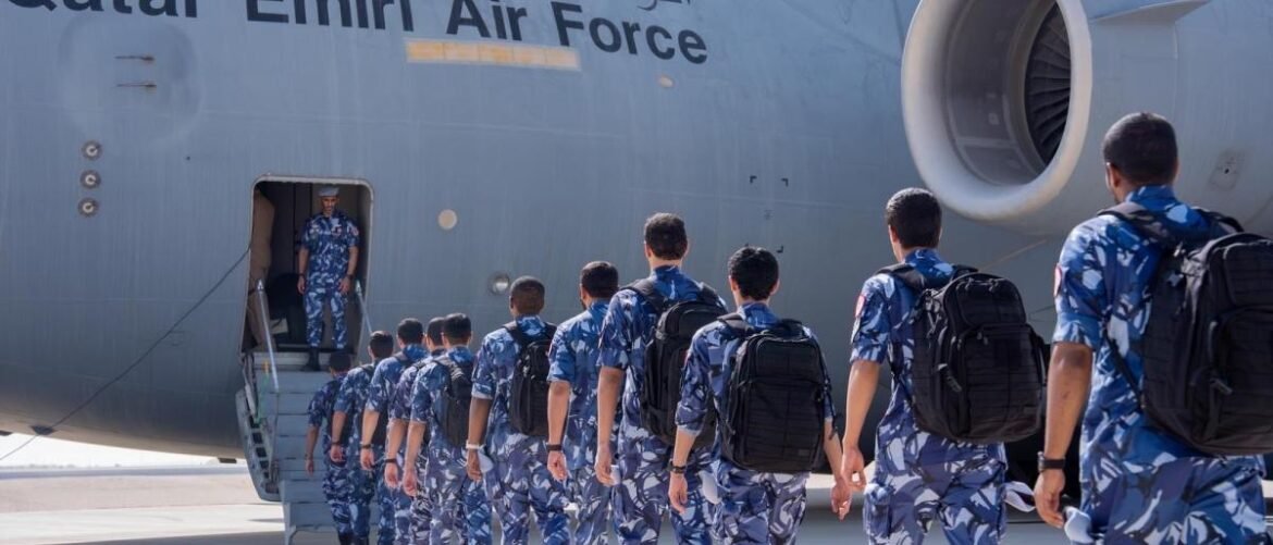 Air Force personnel in blue camouflage boarding a large gray transport aircraft via a mobile staircase.