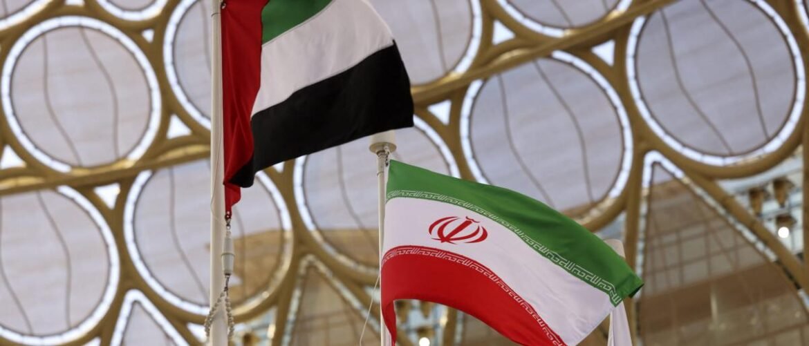 Iranian flag in foreground waving beside another flag, set against a decorative circular lattice canopy.
