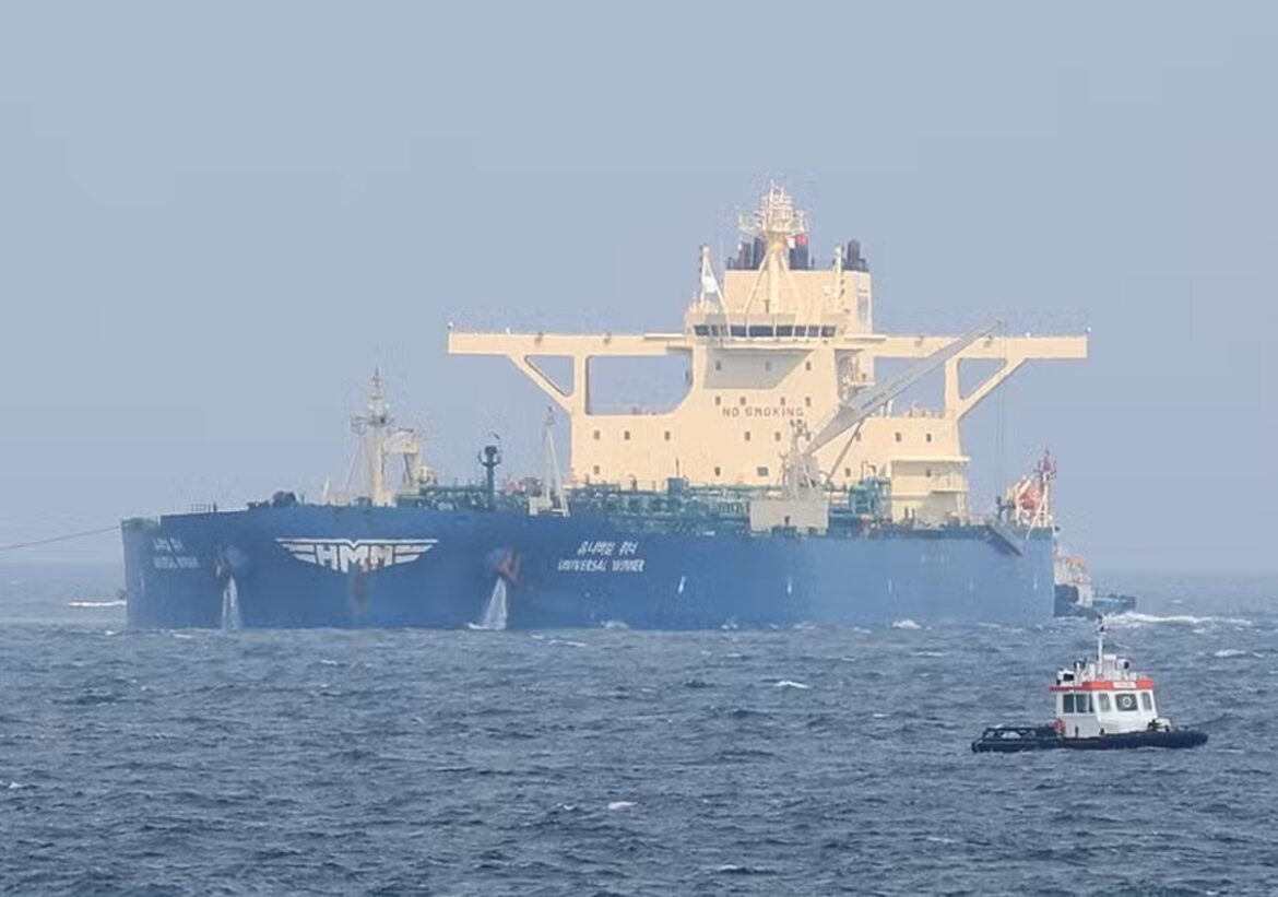 Large blue offshore support vessel with a beige superstructure and a big crane, accompanied by a small tugboat on choppy sea surface.