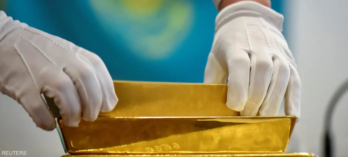 Gloved hands handling a stack of shiny gold bars.