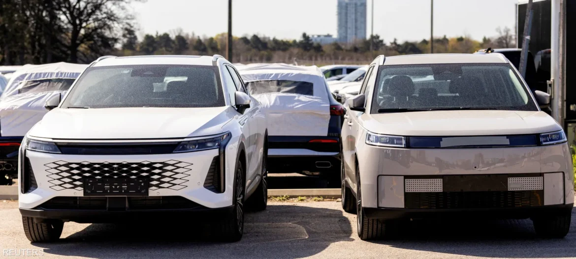 Two white modern SUVs parked side by side in an outdoor car lot with covered vehicles in the background.