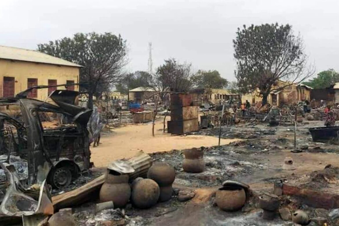 Charred village scene with burnt vehicles, ruined buildings, and scattered clay pots after a fire.