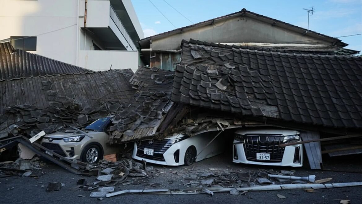 Collapsed tile roof crashing onto three parked cars, debris scattered across a street in an urban area. The image shows a collapsed traditional tile roof resting on a white sedan and two other cars, with rubble and broken tiles everywhere.