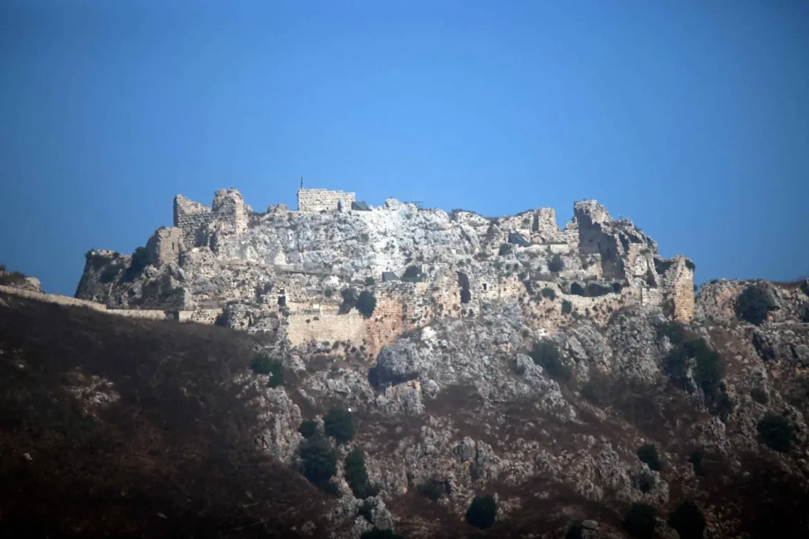 Ancient stone fortress ruin perched on a rocky hillside beneath a clear blue sky.