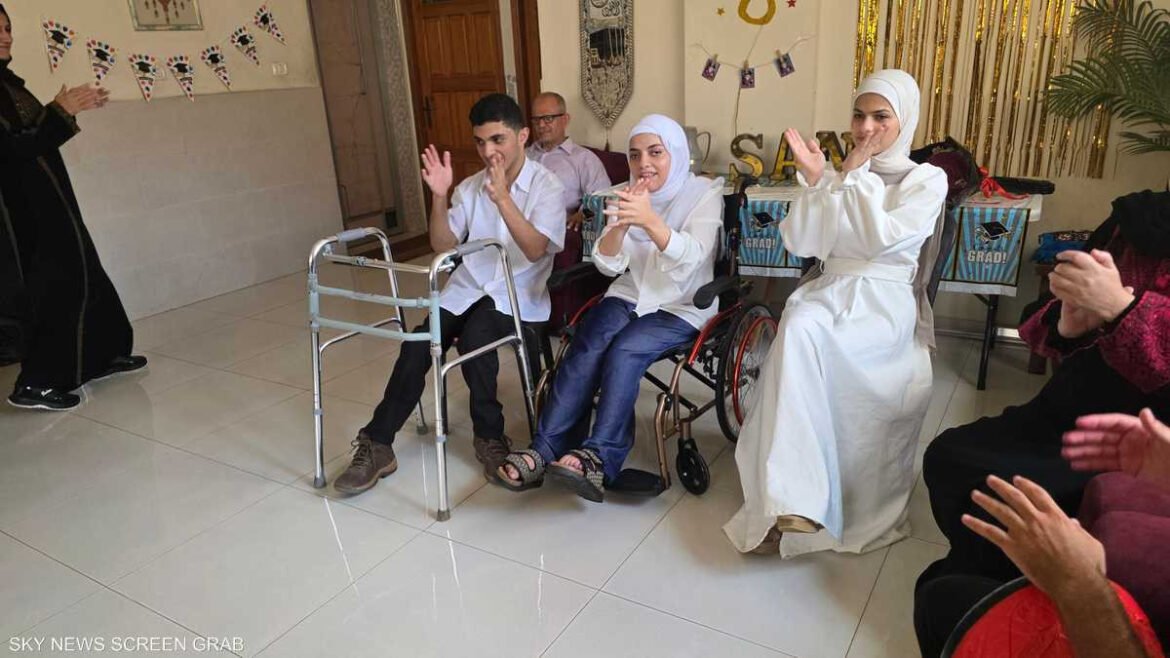 Group of people in wheelchairs clapping during a celebration in a bright room with festive banners on the wall and guests nearby.