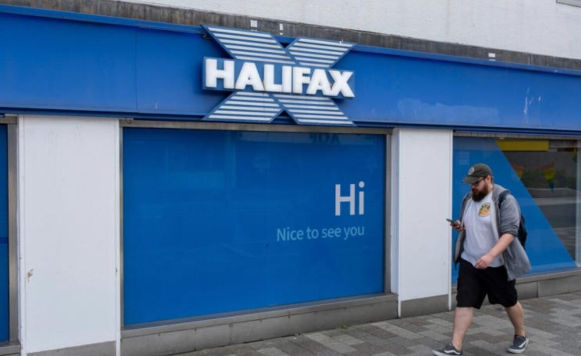 Halifax storefront with a blue facade and a large 'Hi' sign on the window; a man walks by looking at his phone.
