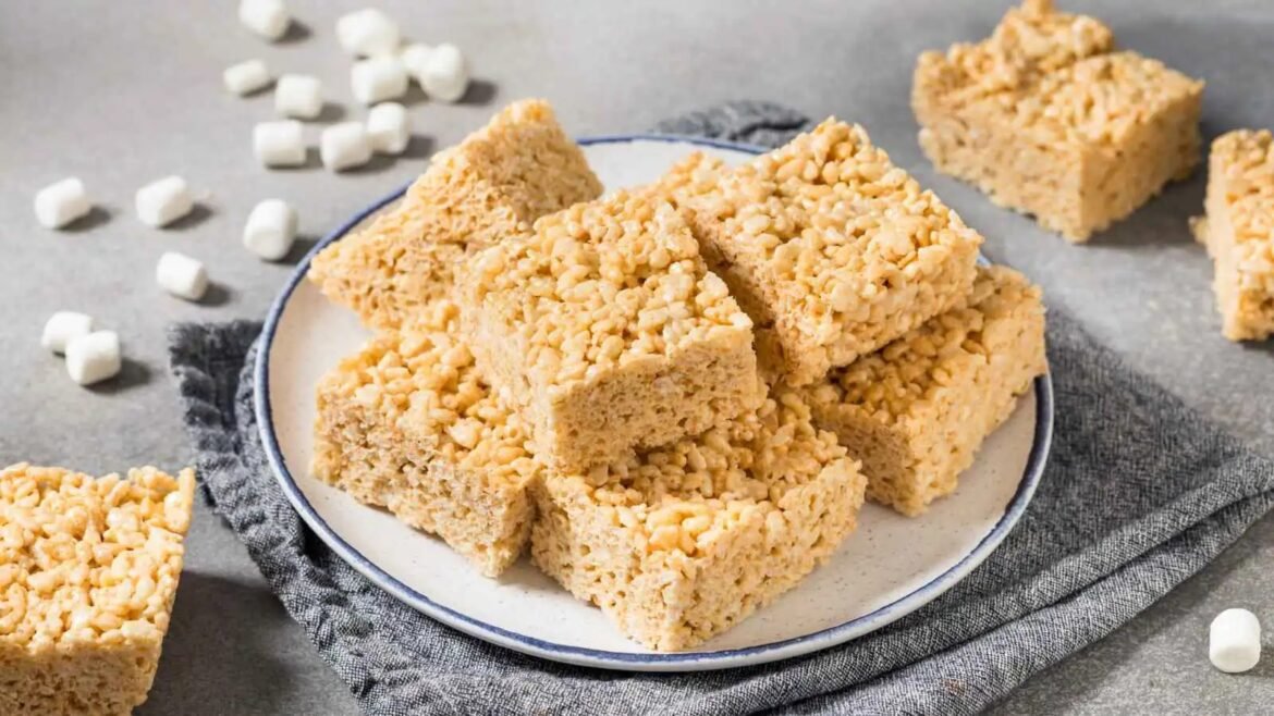 Plate of peanut butter Rice Krispies treats cut into squares, with marshmallows nearby.