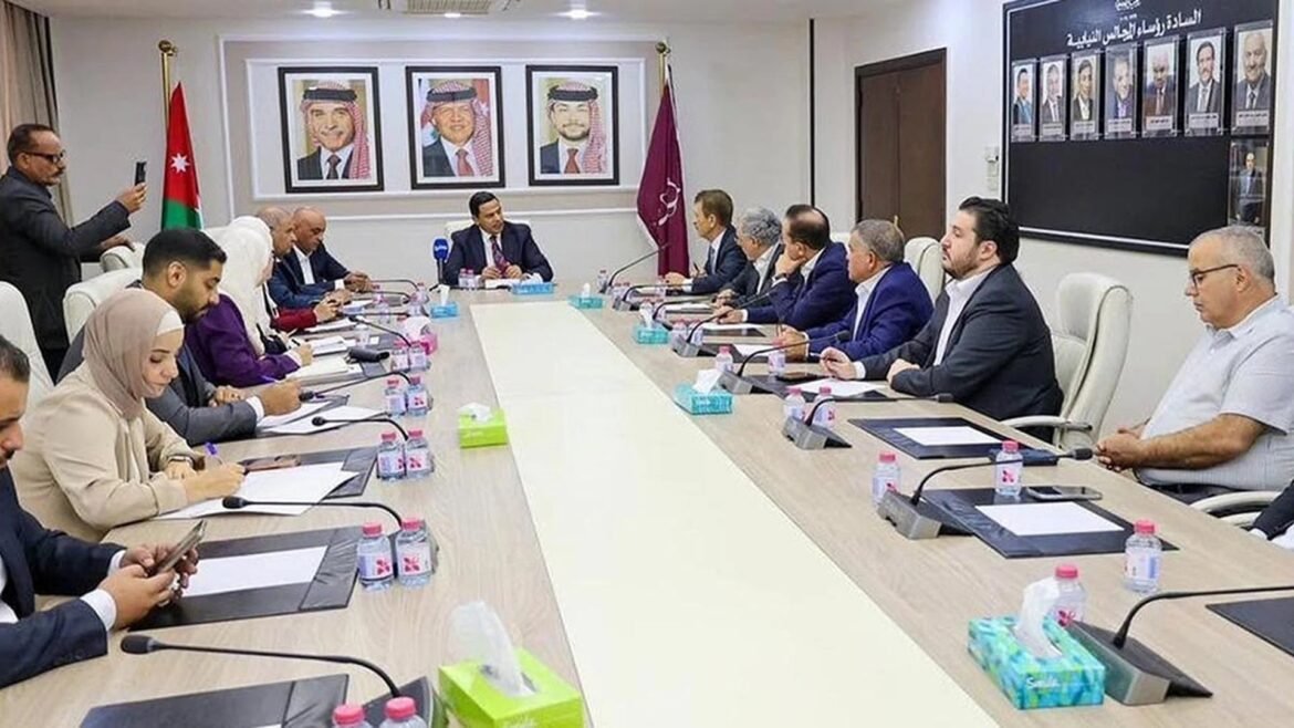 Group of officials in a formal meeting around a long conference table in a bright room with flags and portraits on the wall.