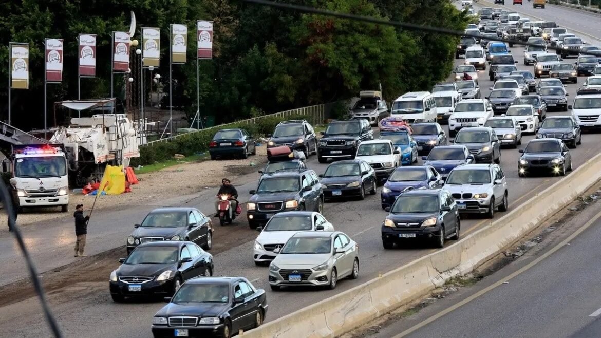 Heavy traffic jam on a multi-lane road with cars bumper-to-bumper and a person signaling on the shoulder nearby.