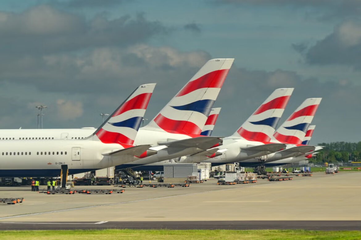 Row of British Airways airplanes parked at an airport gate with ground crew and luggage carts nearby.