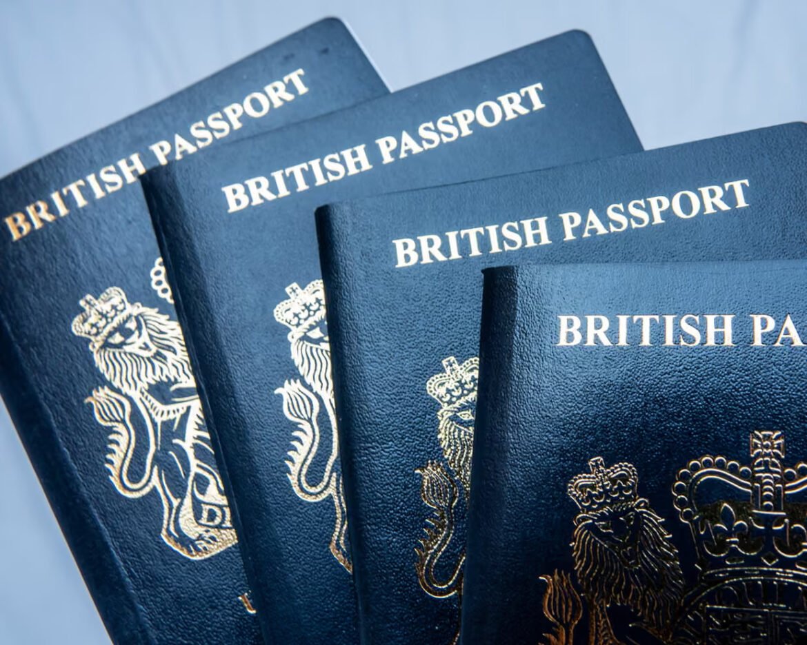 Several blue British passports fanned out, displaying the gold crest and text on the covers.